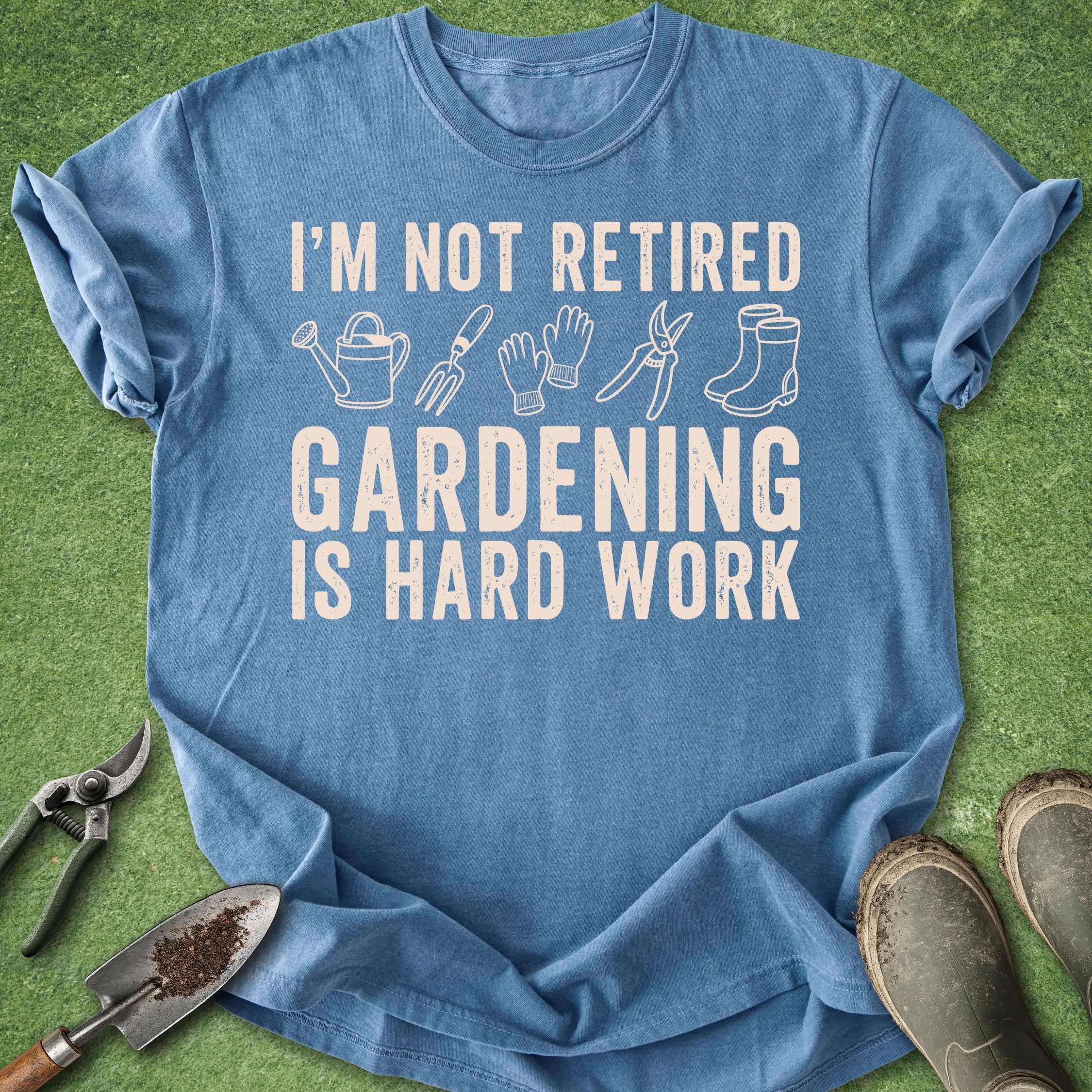 Blue t-shirt with gardening-themed text and graphics on a grass background