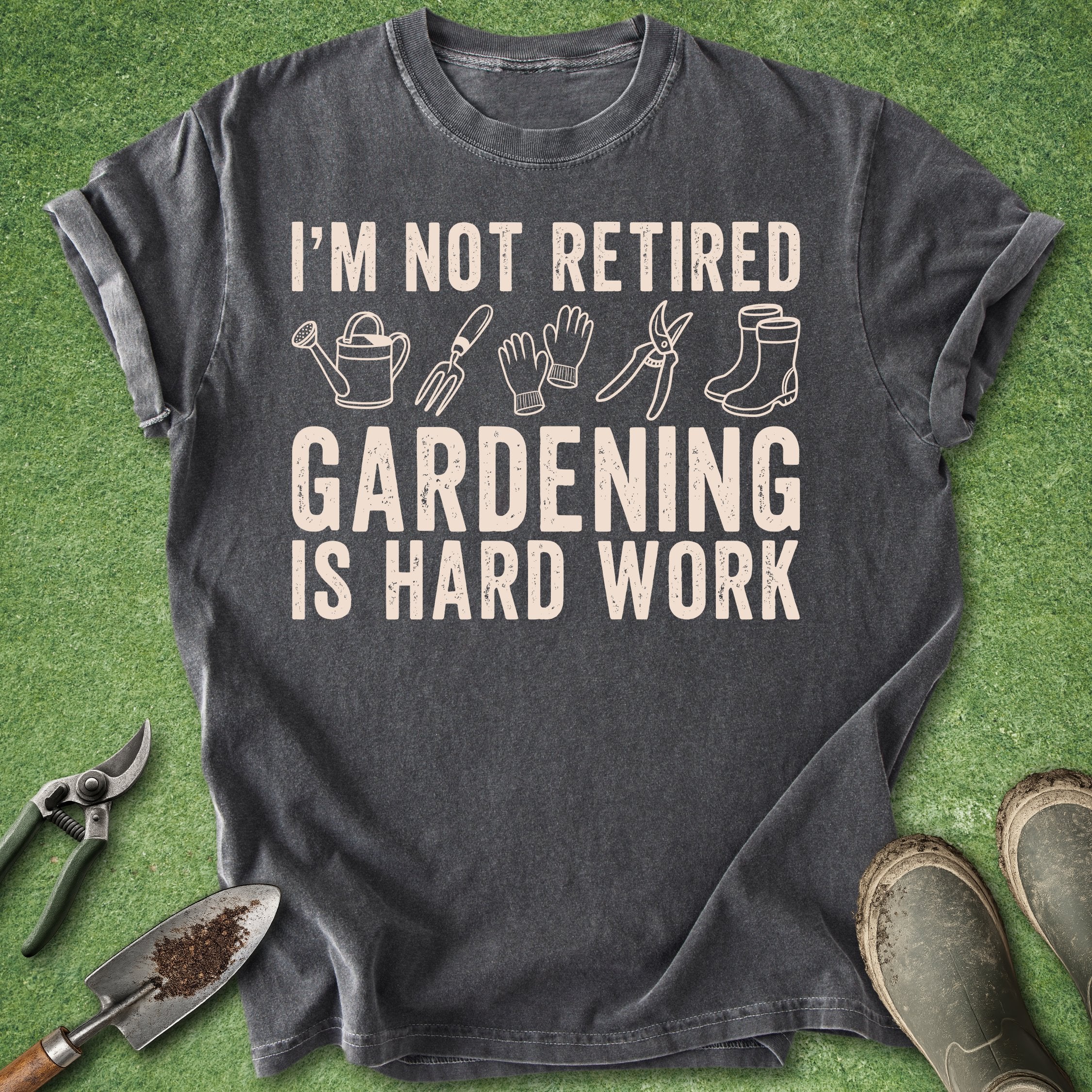 Gray t-shirt with gardening-themed text and icons on a green grass background