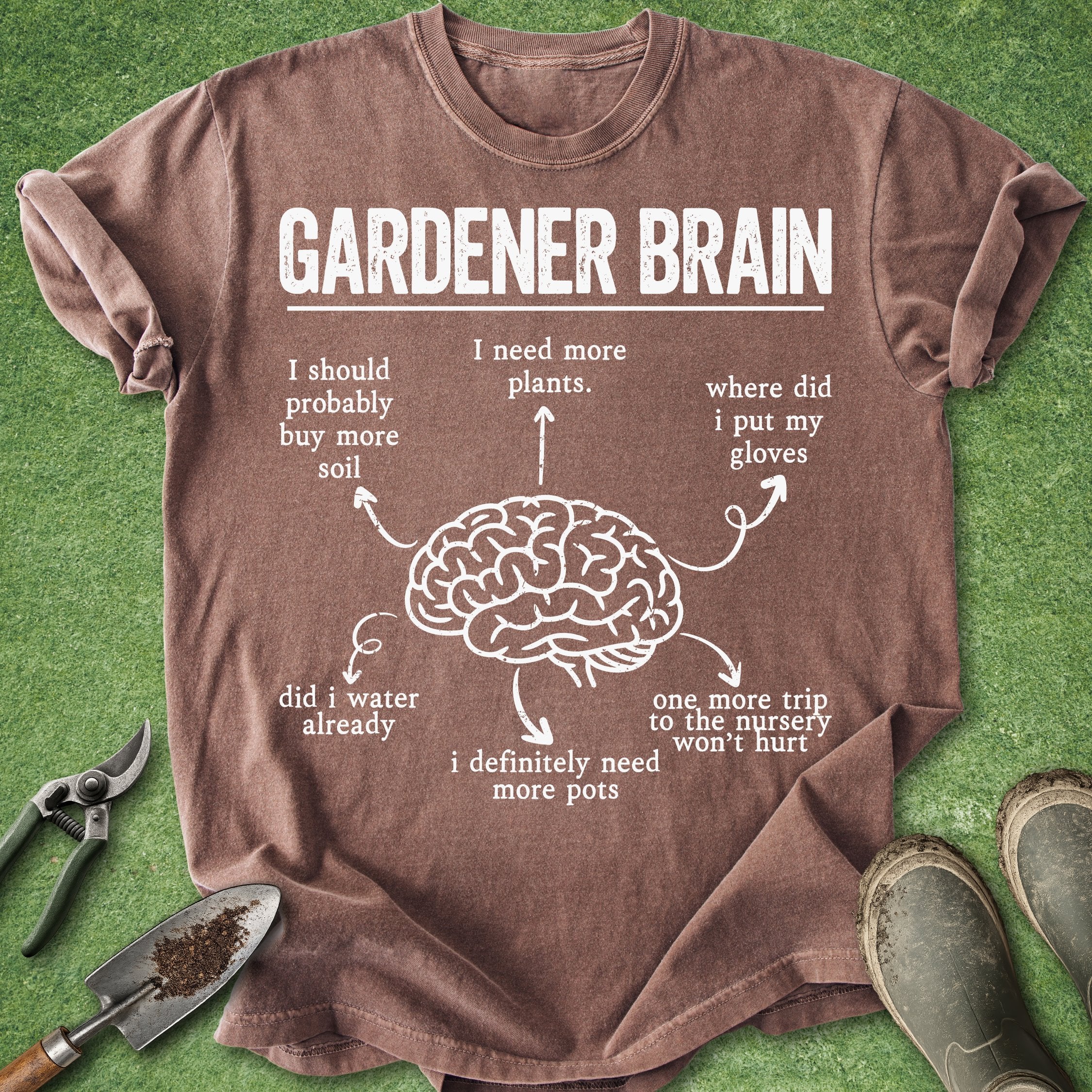Brown t-shirt with 'Gardener Brain' graphic on a grass background with gardening tools.