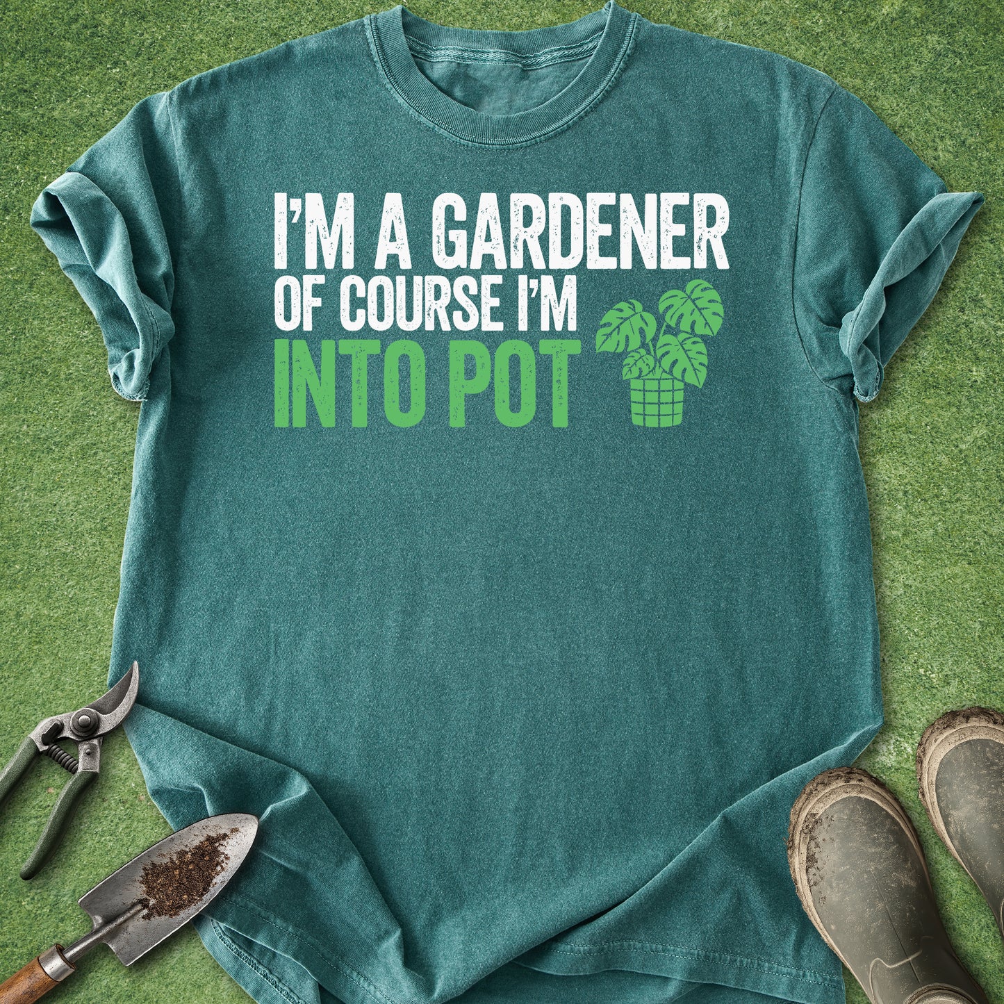 Teal t-shirt with gardening-themed text and graphics on a grass background