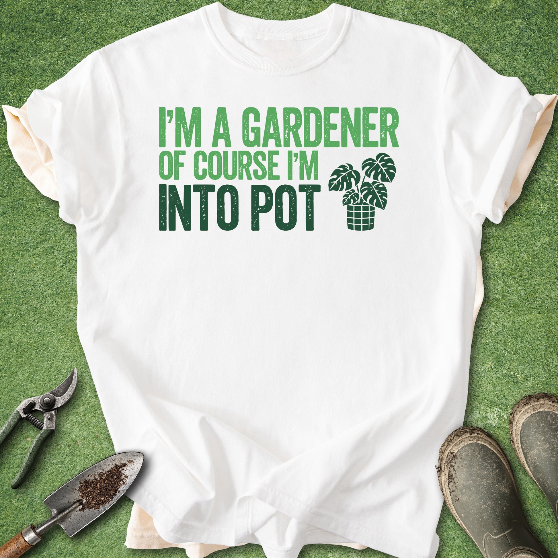 White t-shirt with green text and graphic on a grass background