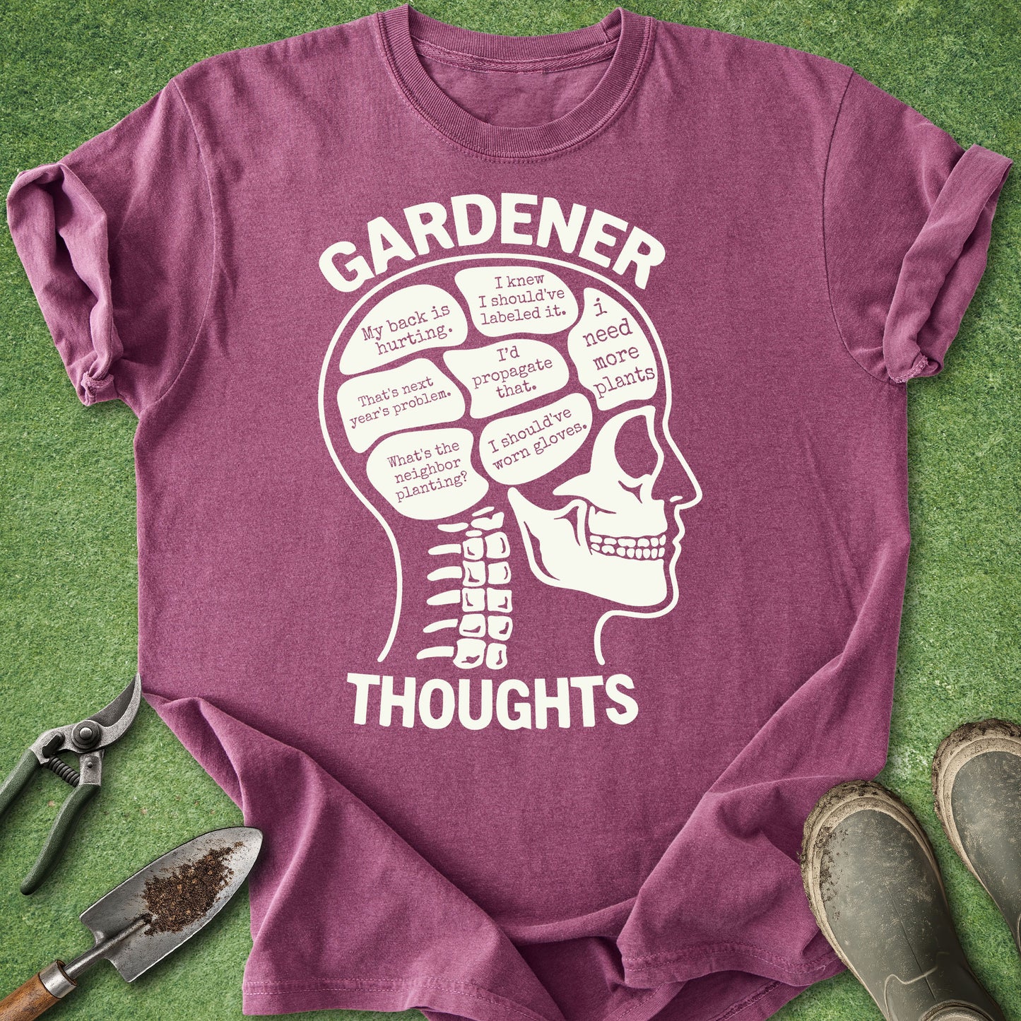 Purple t-shirt with a skull graphic and 'Gardener Thoughts' text on a grass background.