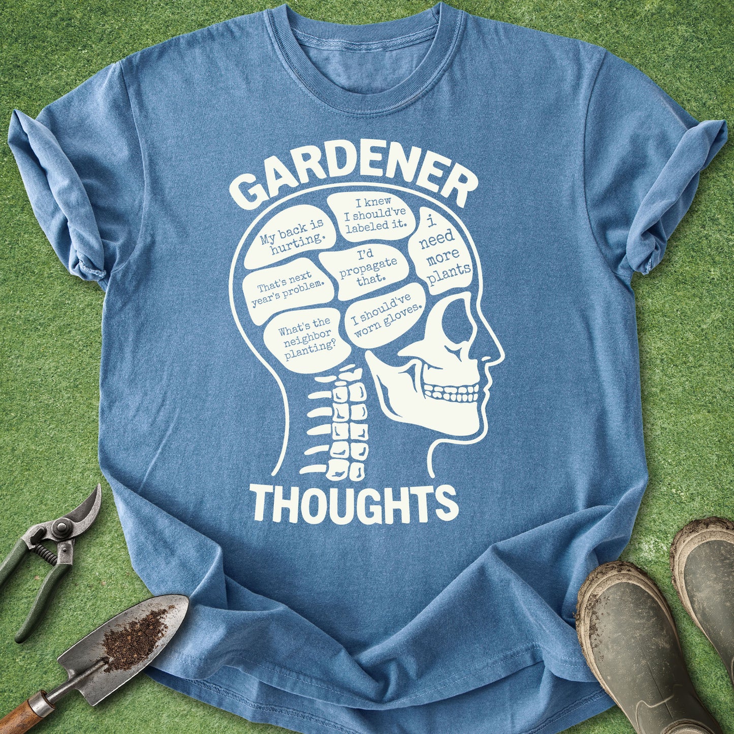 Blue t-shirt with a white skull graphic and text on a green grass background