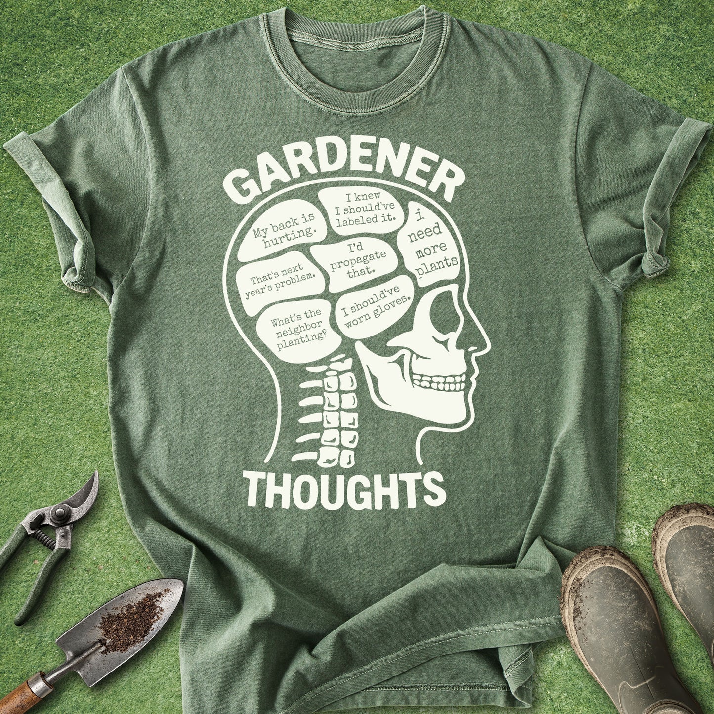 Green t-shirt with a skull graphic and 'Gardener Thoughts' text on a grass background.