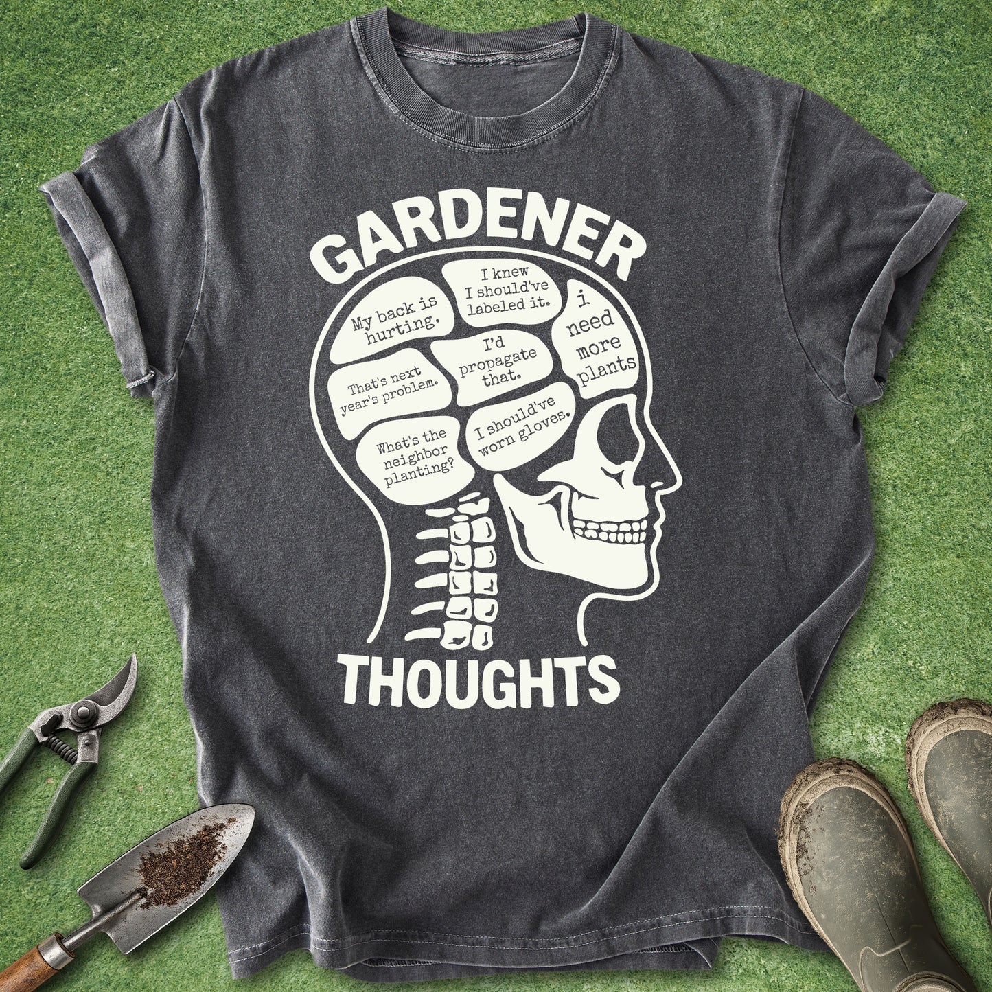 Gray t-shirt with skull design and 'Gardener Thoughts' text on a green grass background.