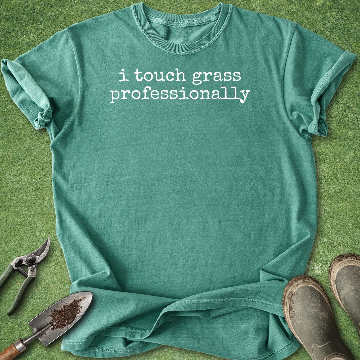 Green Comfort Colors t-shirt featuring the funny phrase "i touch grass professionally" in a minimalist white typewriter font.