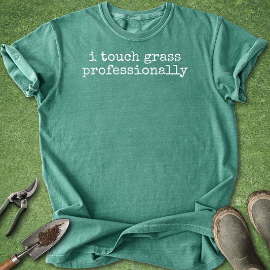 Green Comfort Colors t-shirt featuring the funny phrase "i touch grass professionally" in a minimalist white typewriter font.