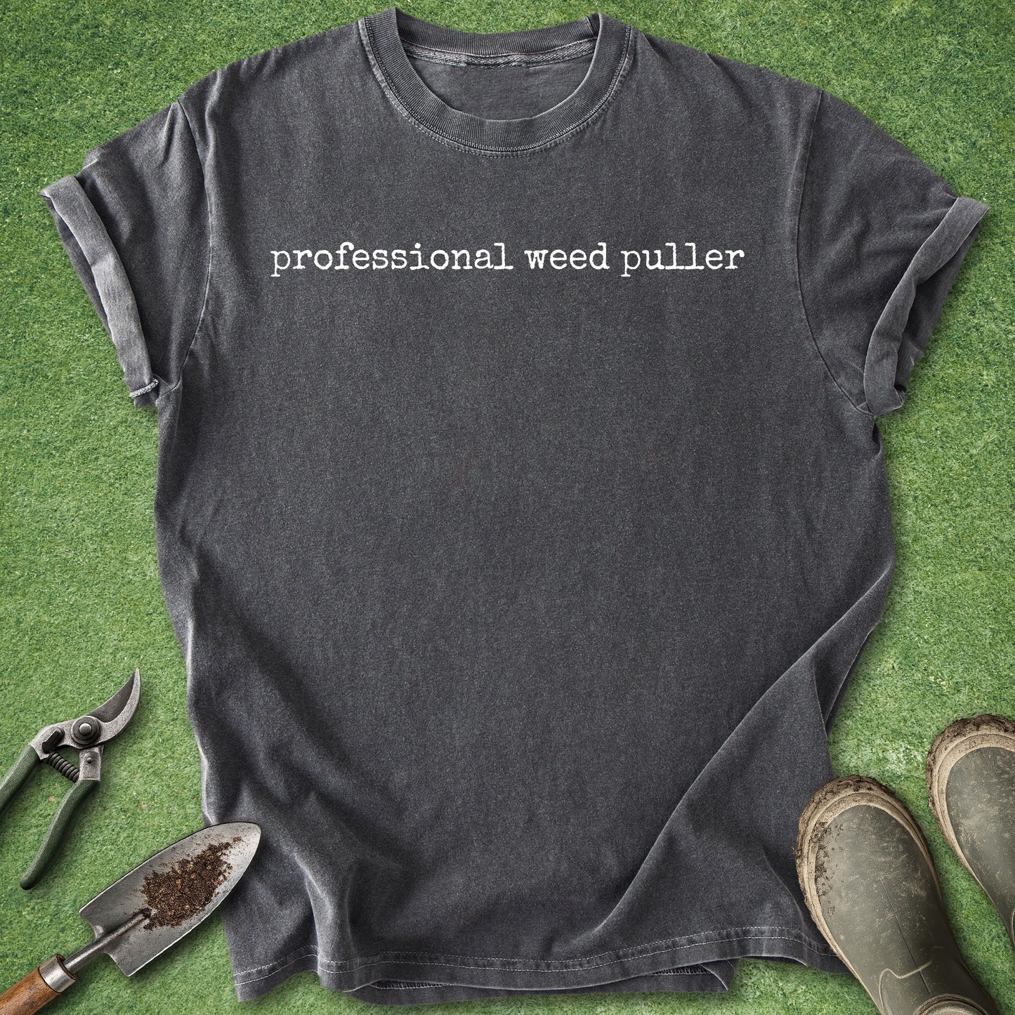 Gray t-shirt with 'professional weed puller' text on a green grass background with gardening tools.