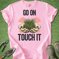 Pink t-shirt with 'Go on, touch it' graphic and gardening tools on a green background
