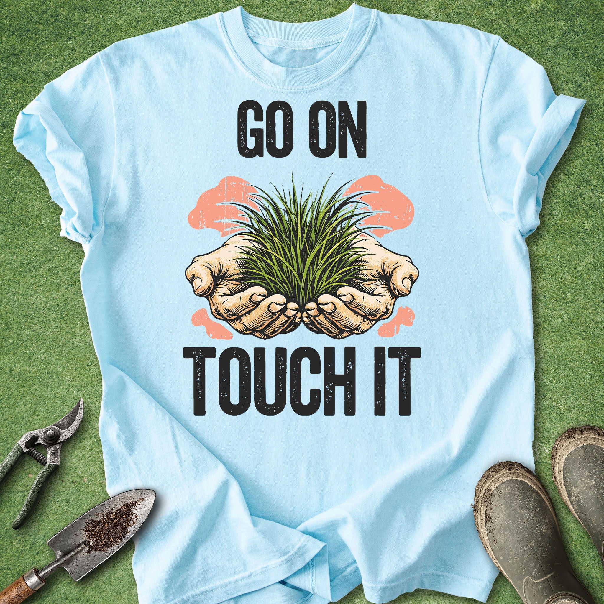 Light blue t-shirt with hands holding grass graphic and 'Go on Touch It' text on a green background.