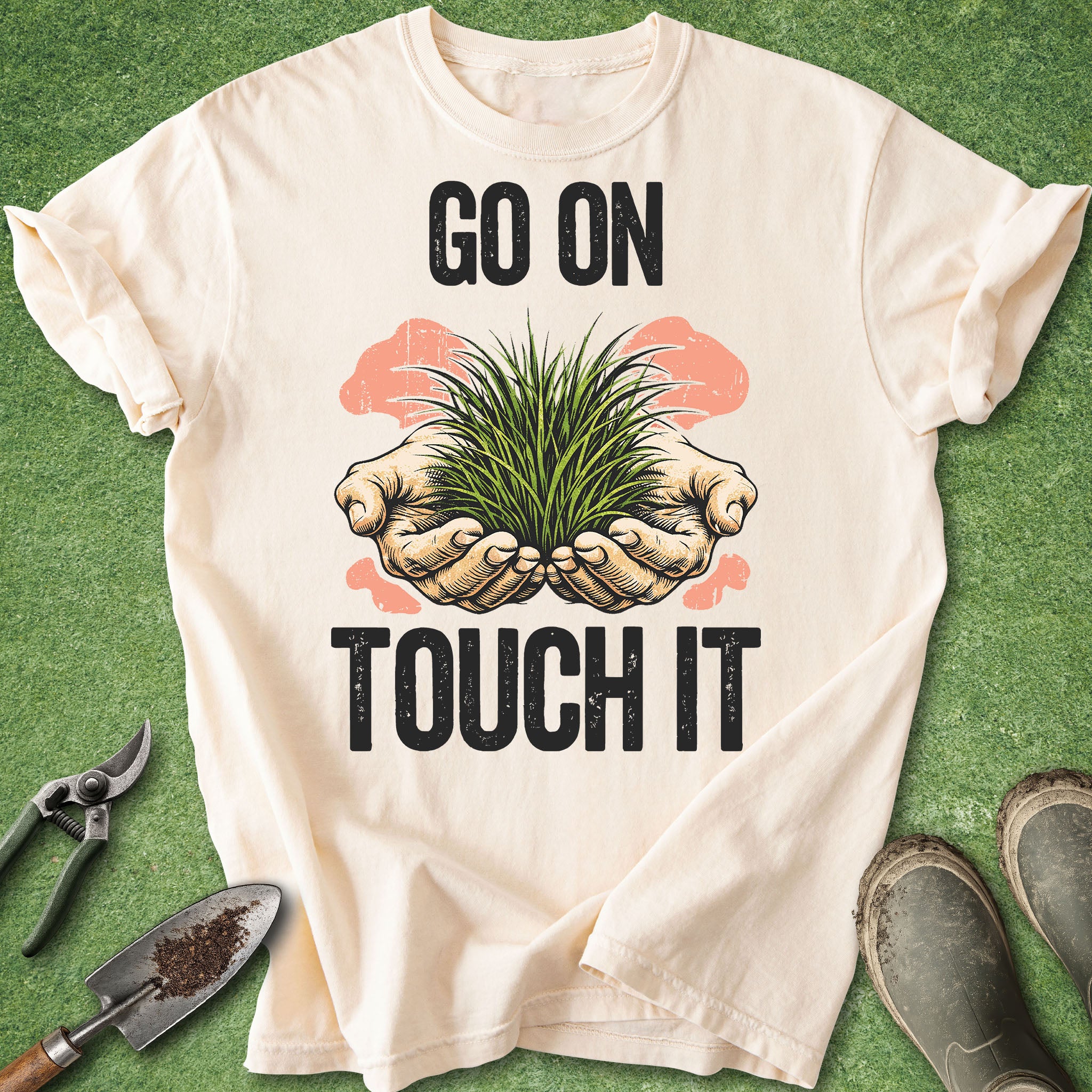 White t-shirt with 'Go on, touch it' graphic and gardening tools on a green background