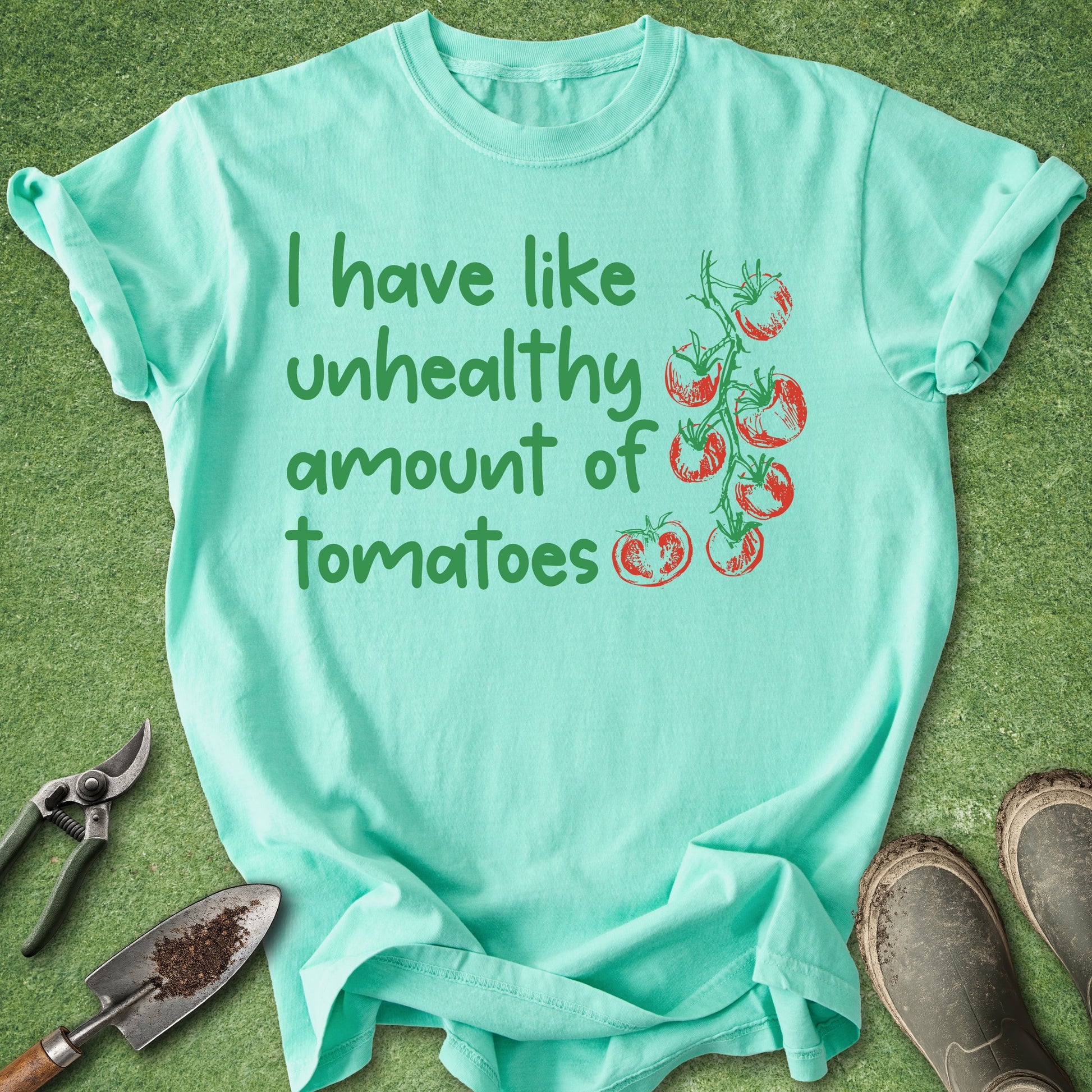 Mint green t-shirt with tomato graphic and text on a grass background
