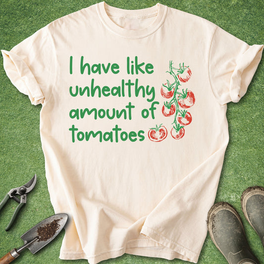 Beige t-shirt with green text and tomato graphics on a green background with gardening tools.