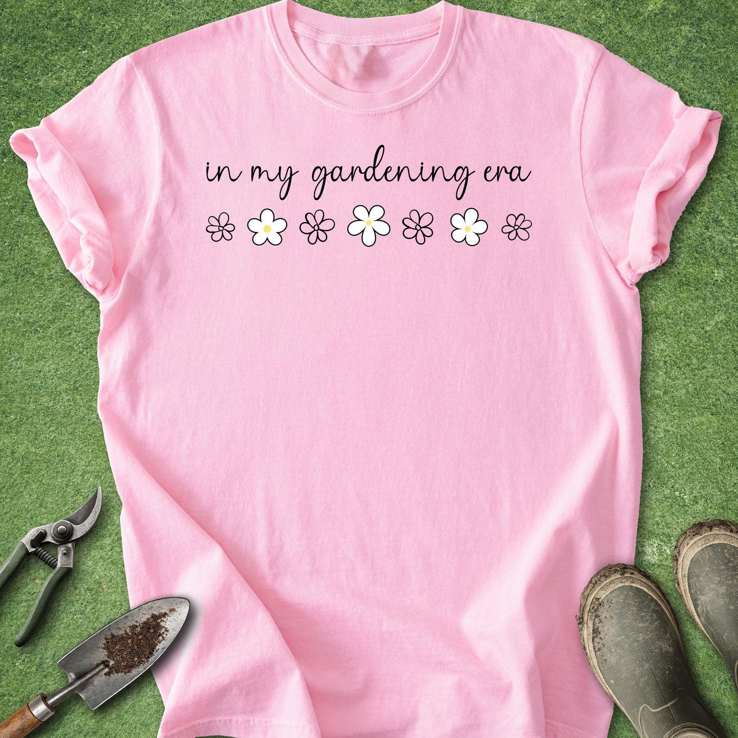 Pink t-shirt with 'in my gardening era' text and flowers on a grass background