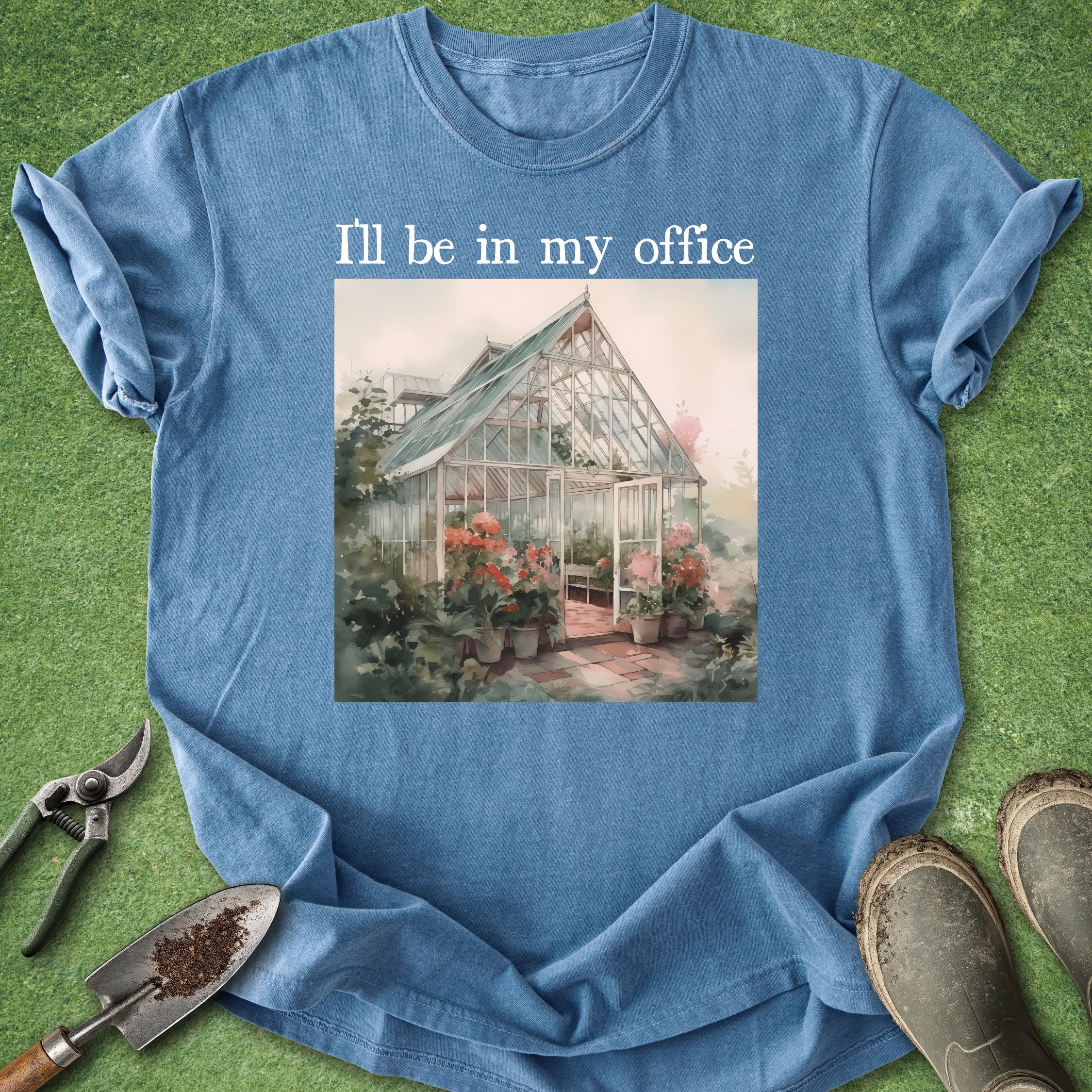 Blue t-shirt with a greenhouse illustration and text 'I'll be in my office' on a grass background.