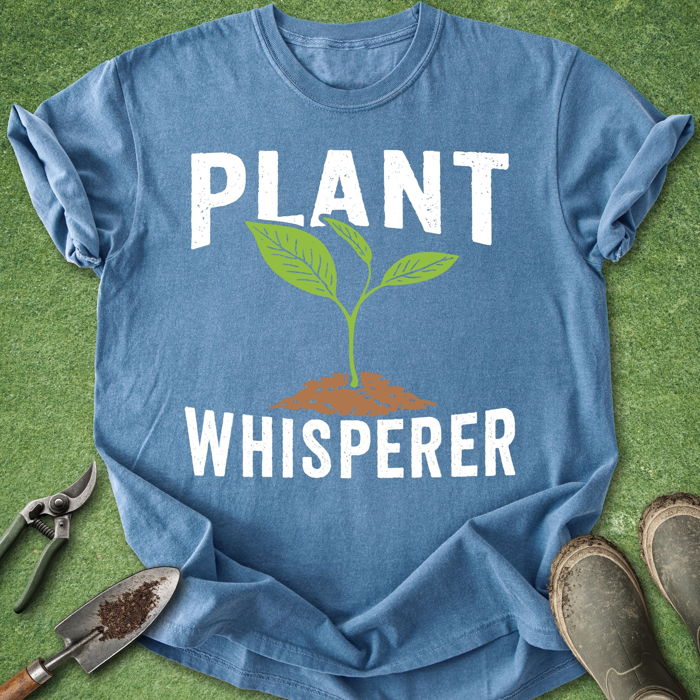 Blue t-shirt with 'Plant Whisperer' design on a grass background
