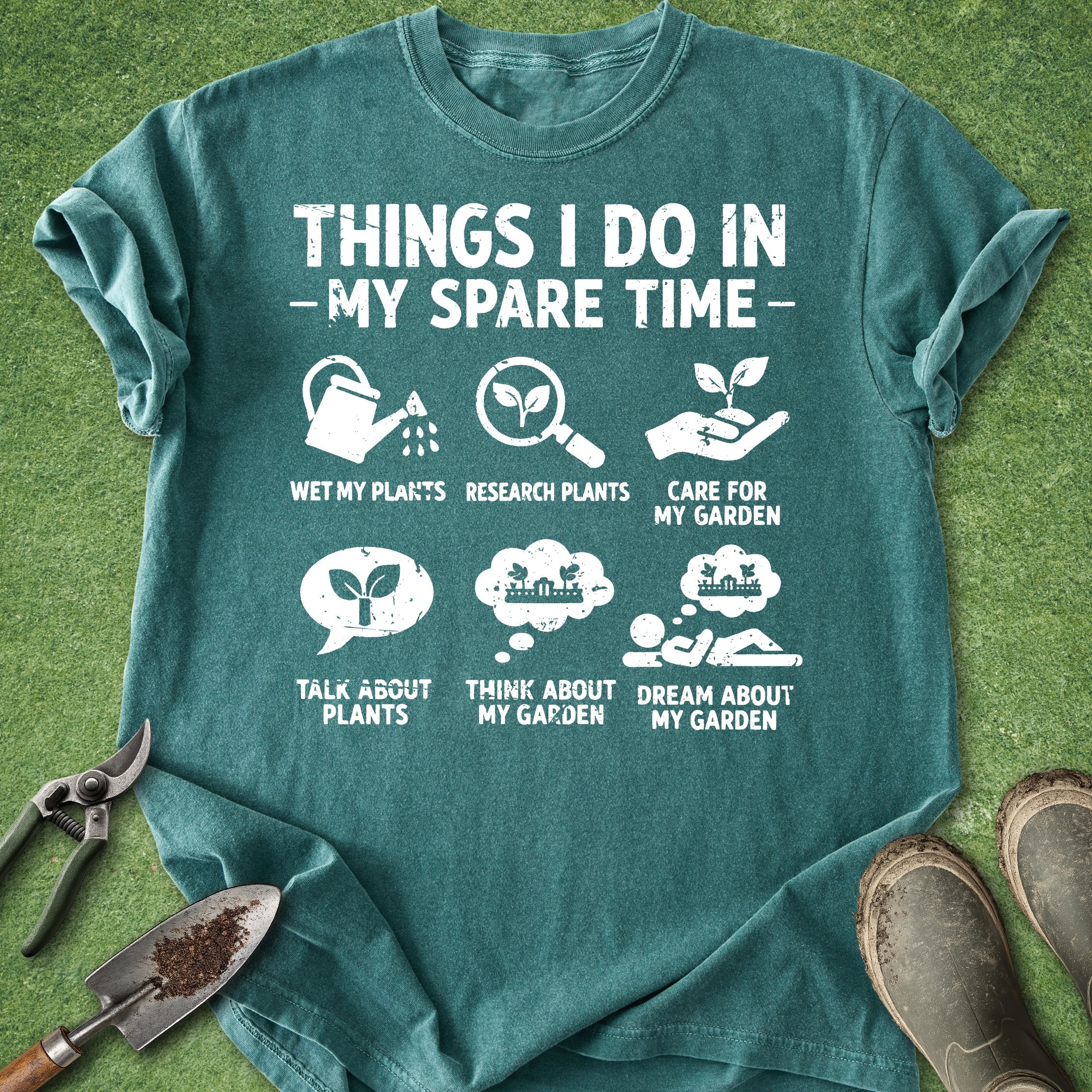 Teal t-shirt with gardening-themed text and icons on a grass background