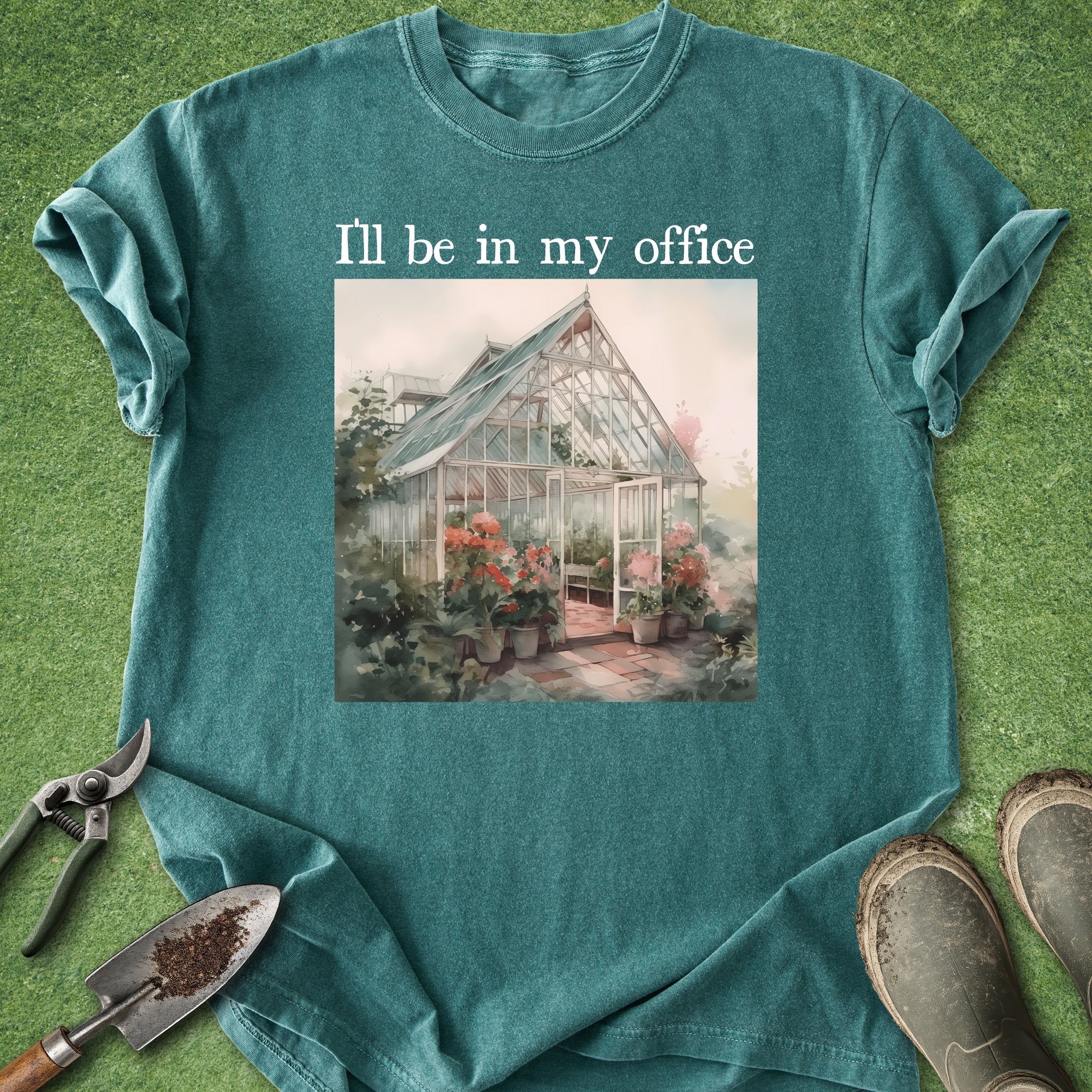 Teal t-shirt with a greenhouse graphic and text 'I'll be in my office' on a grassy background.