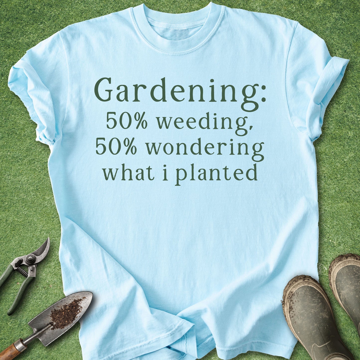 Light blue t-shirt with gardening text on a grass background with gardening tools.