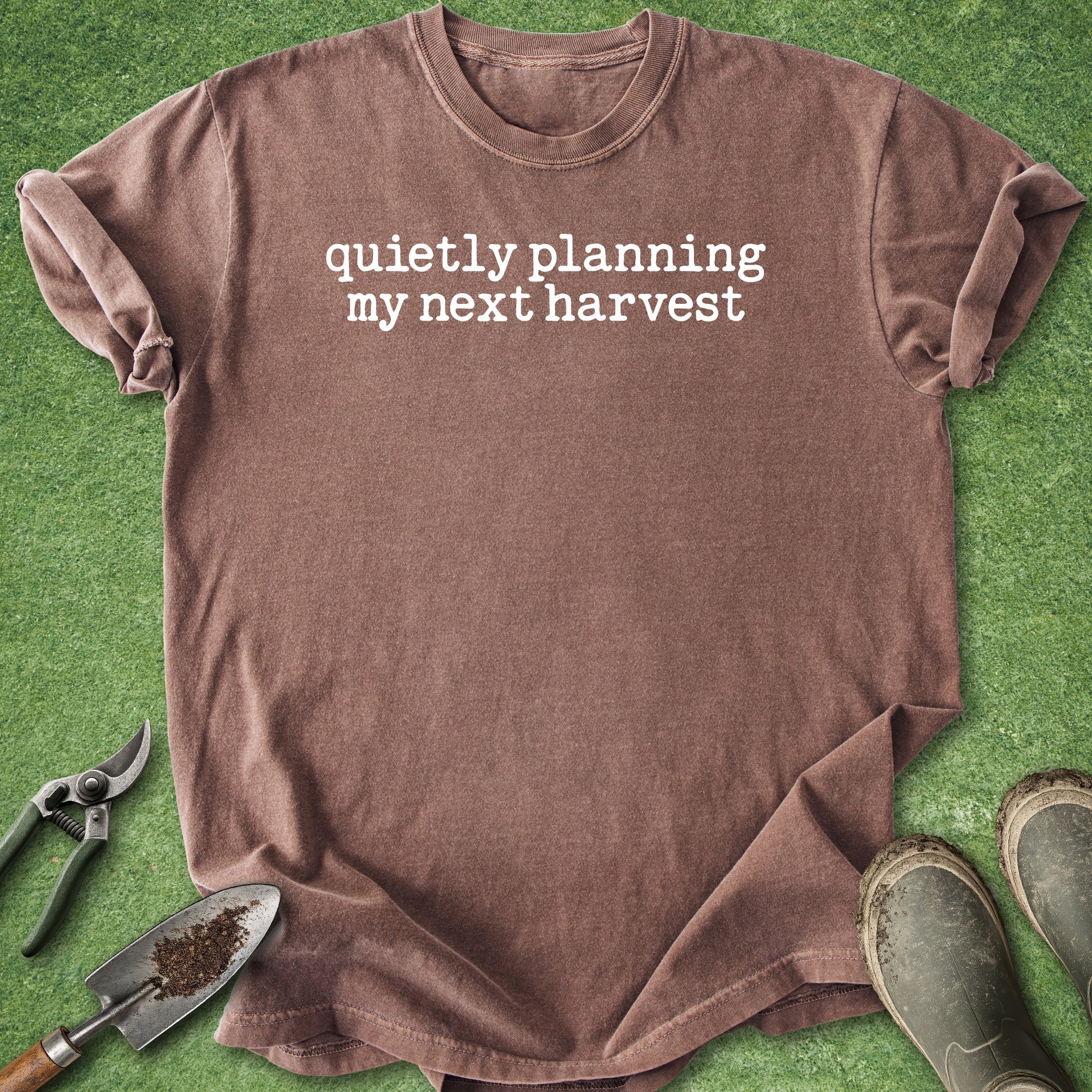 Brown t-shirt with 'quietly planning my next harvest' text on a green background with gardening tools.