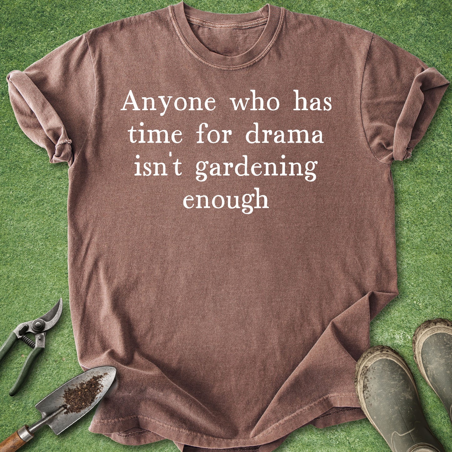 Brown t-shirt with humorous text on a green background with gardening tools.