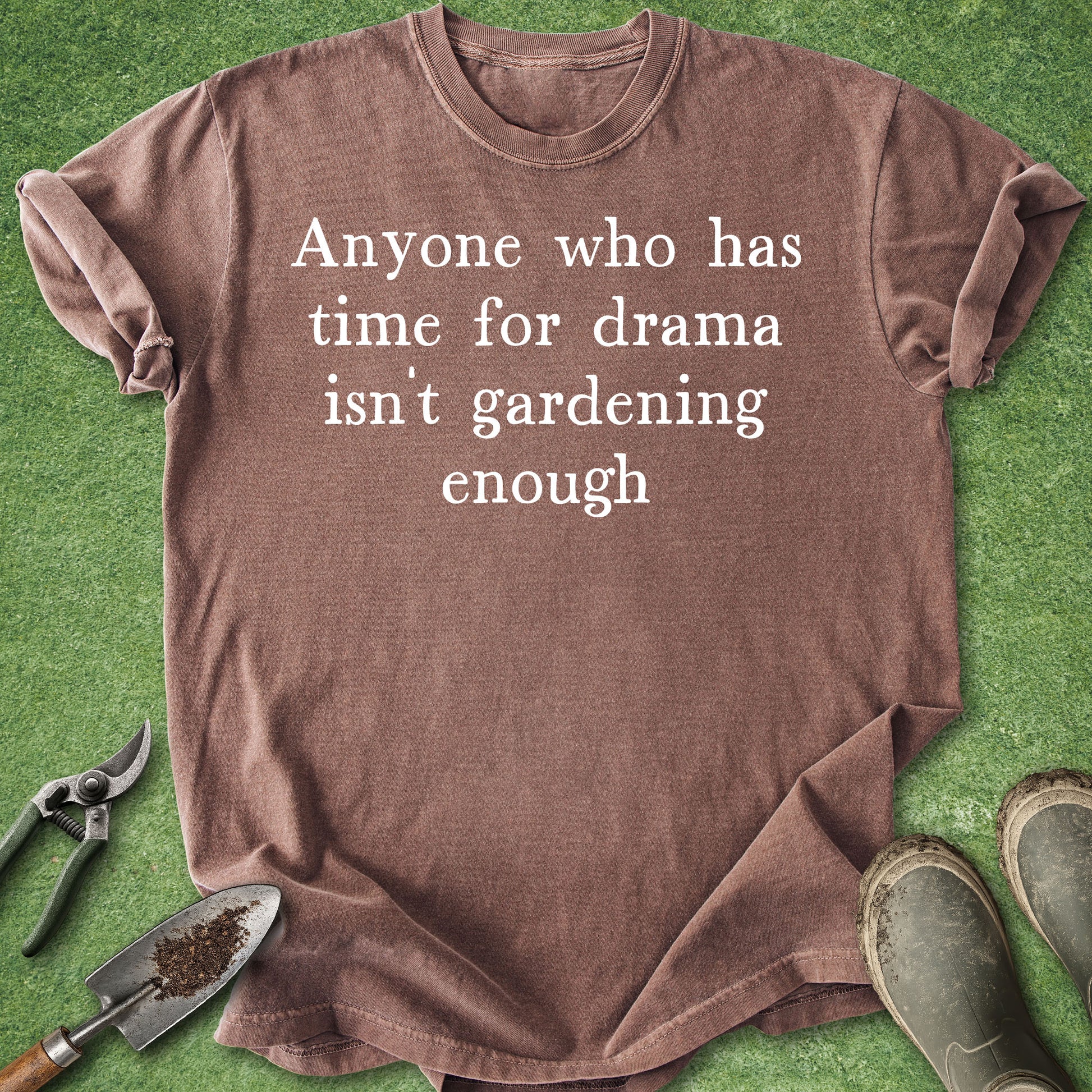 Brown t-shirt with humorous text on a green background with gardening tools.