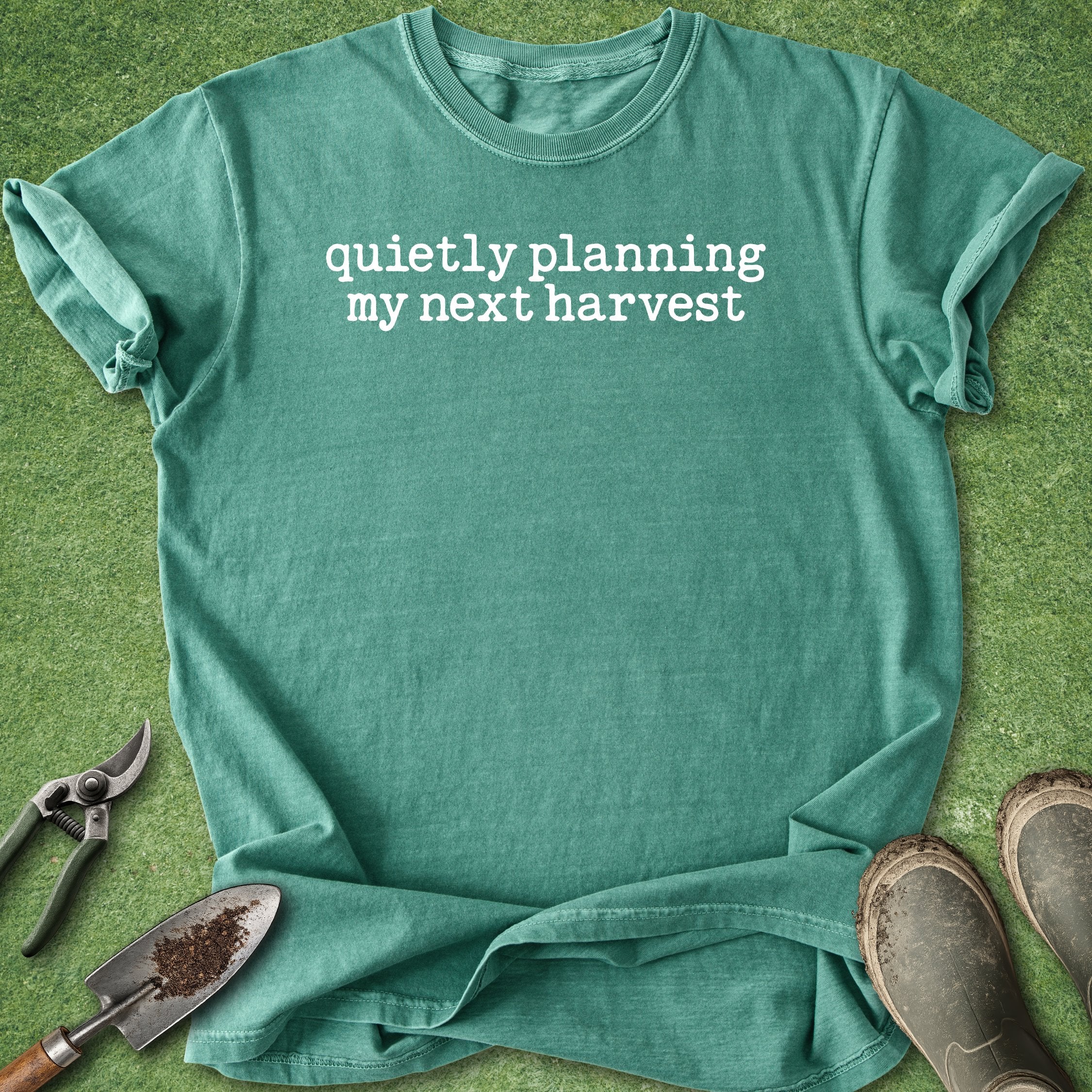 Green t-shirt with 'quietly planning my next harvest' text on a green background with gardening tools.