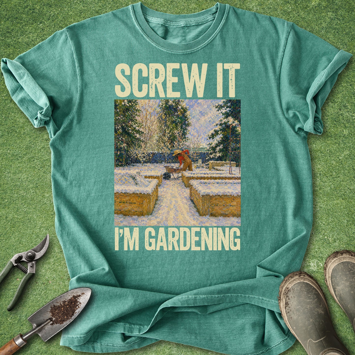 Teal t-shirt with 'Screw it, I'm gardening' text and garden-themed graphic on a grass background.