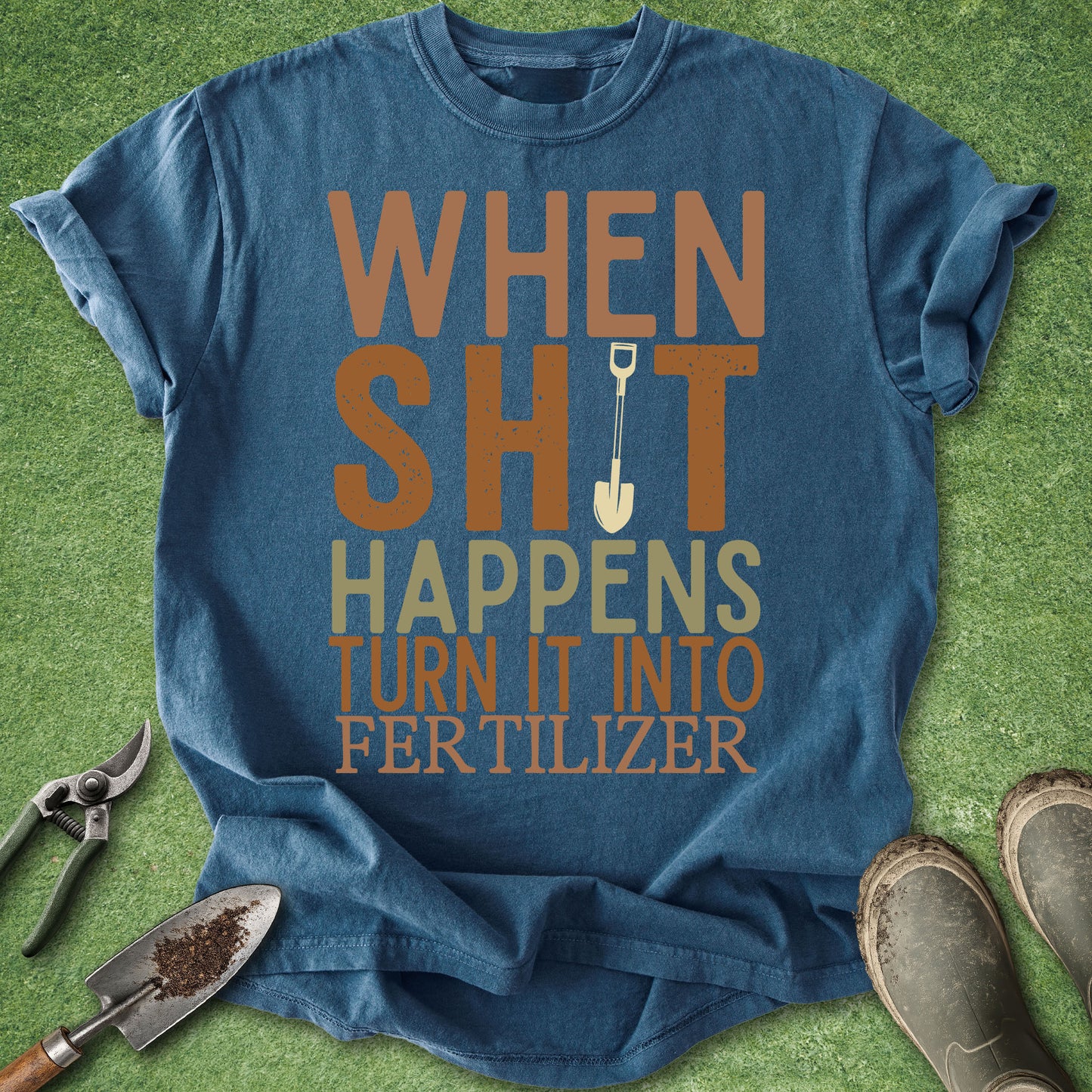 Blue t-shirt with humorous text on a grassy background with gardening tools.