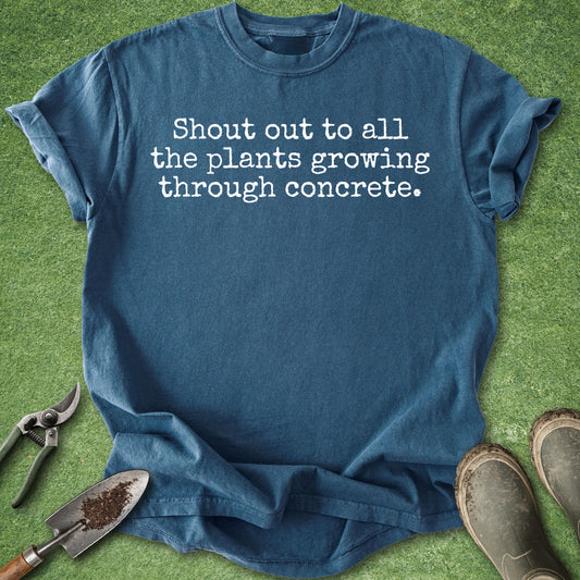 Comfort Colors midnight blue t-shirt featuring the phrase "Shout out to all the plants growing through concrete." in a minimalist white typewriter-style font.