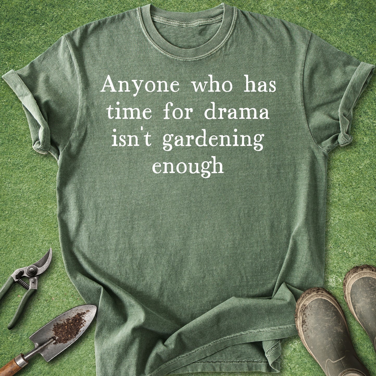 Green t-shirt with humorous text on a grass background with gardening tools.