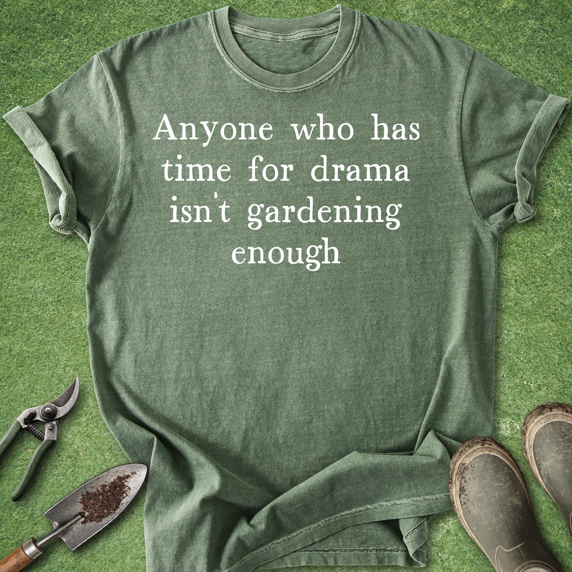 Green t-shirt with humorous text on a grass background with gardening tools.