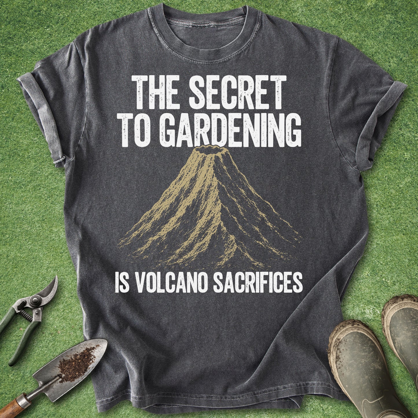 Comfort Colors pepper t-shirt featuring a vintage volcano illustration with the humorous quote "The Secret to Gardening Is Volcano Sacrifices" in distressed white lettering.