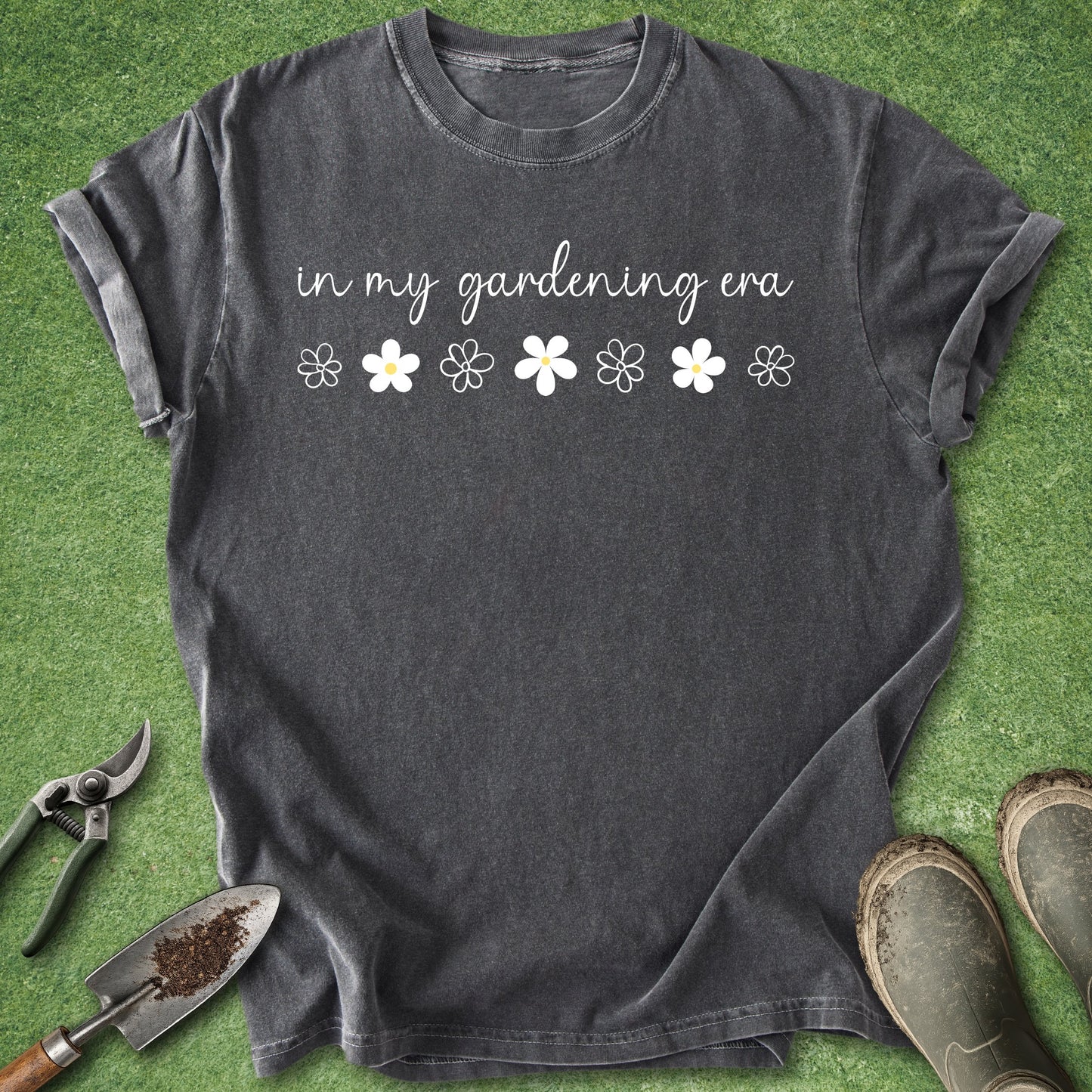 Black t-shirt with 'in my gardening era' text and flower graphics on a grass background