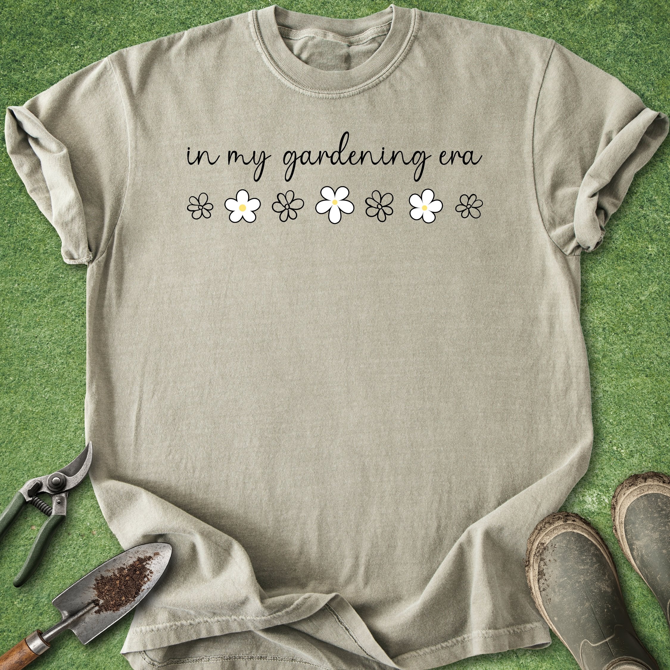 Beige t-shirt with 'in my gardening era' text and flower graphics on a green background