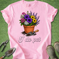 Pink t-shirt with a flower pot and gardening tools graphic on a green background