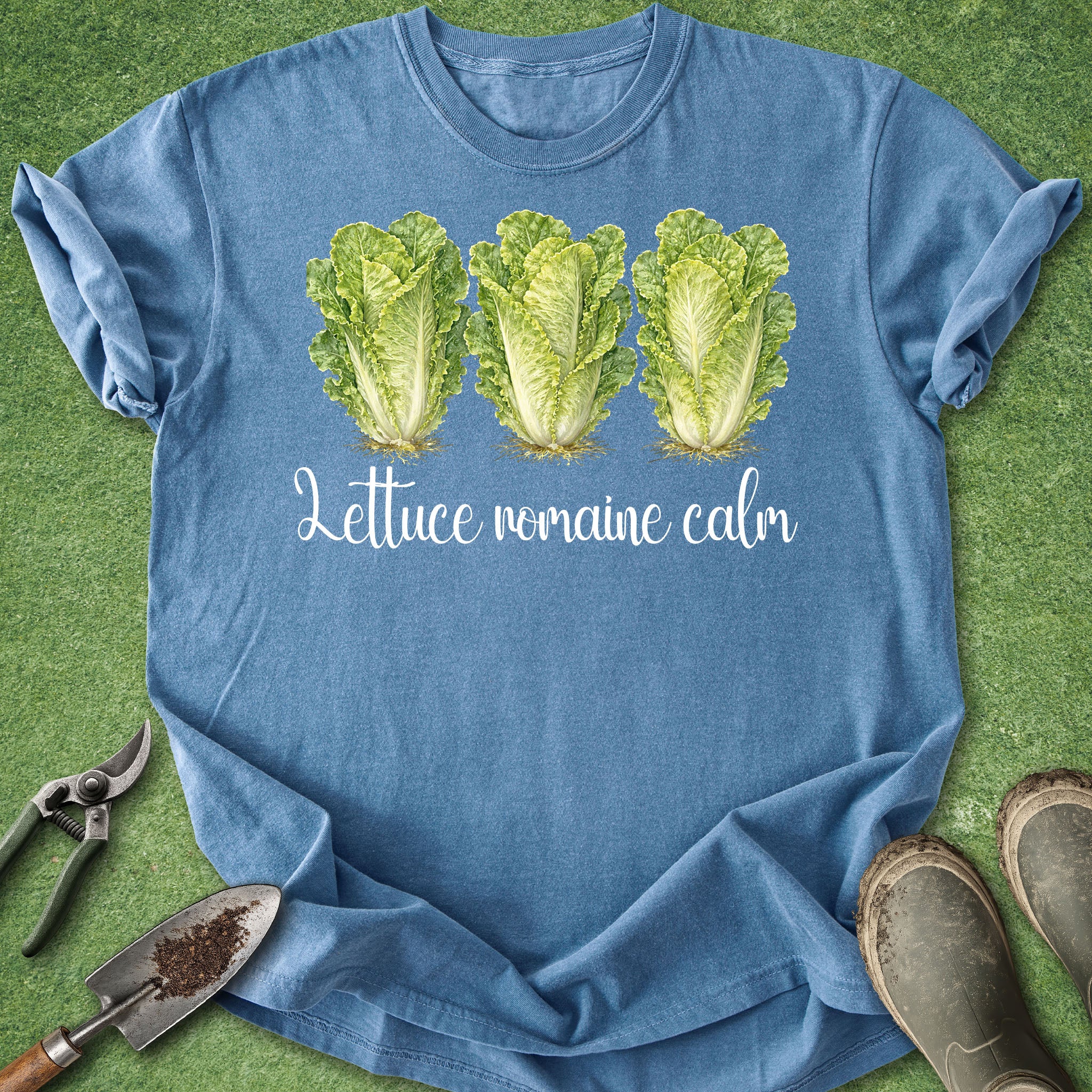 Blue t-shirt with lettuce graphic and text on a green grass background