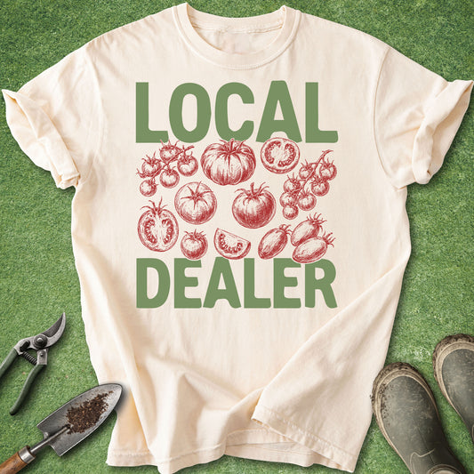 Ivory Comfort Colors t-shirt featuring the phrase "LOCAL DEALER" with vintage red tomato illustrations including cherry tomatoes, heirloom tomatoes, and sliced tomatoes arranged in the center.