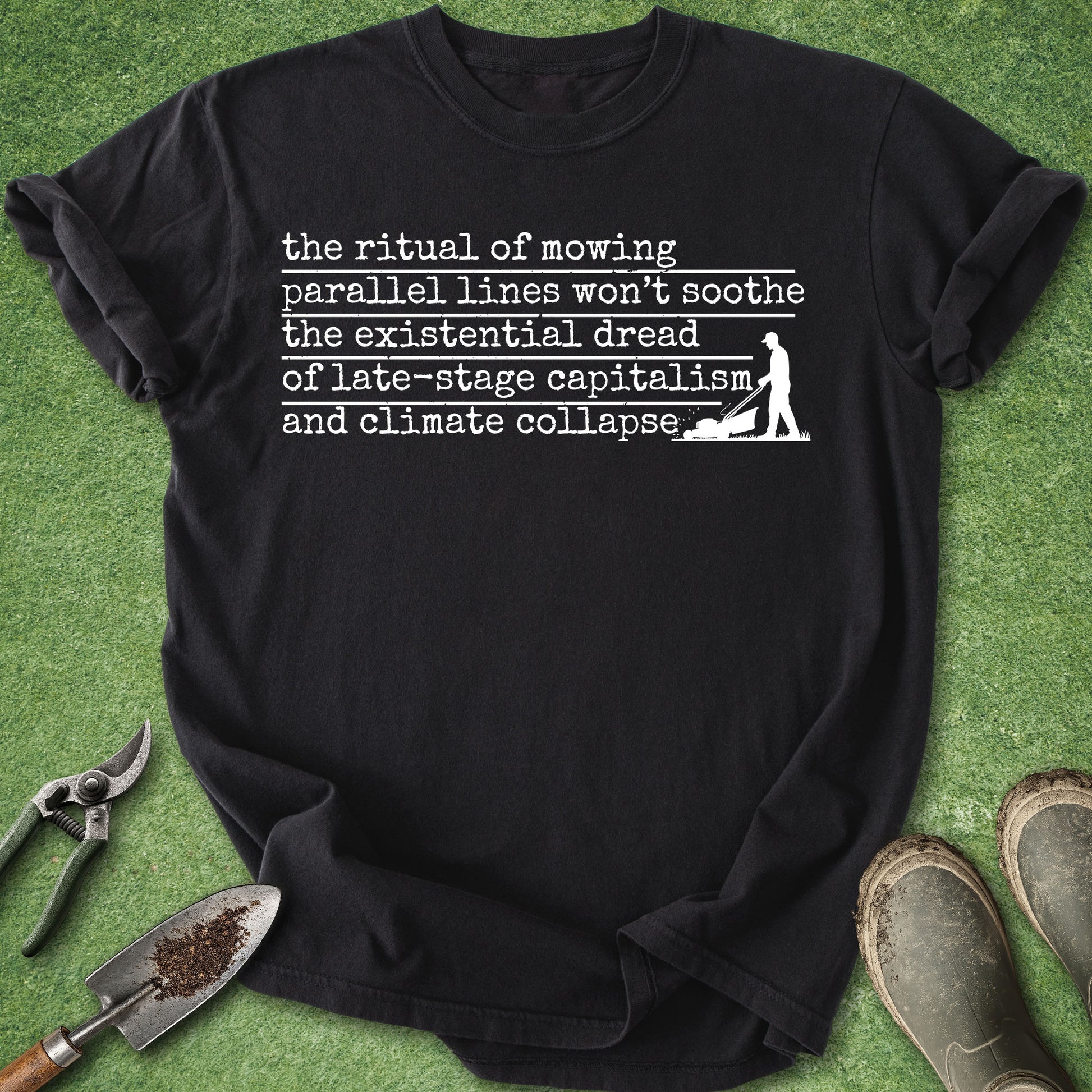 Black t-shirt with white text on a grass background with gardening tools.