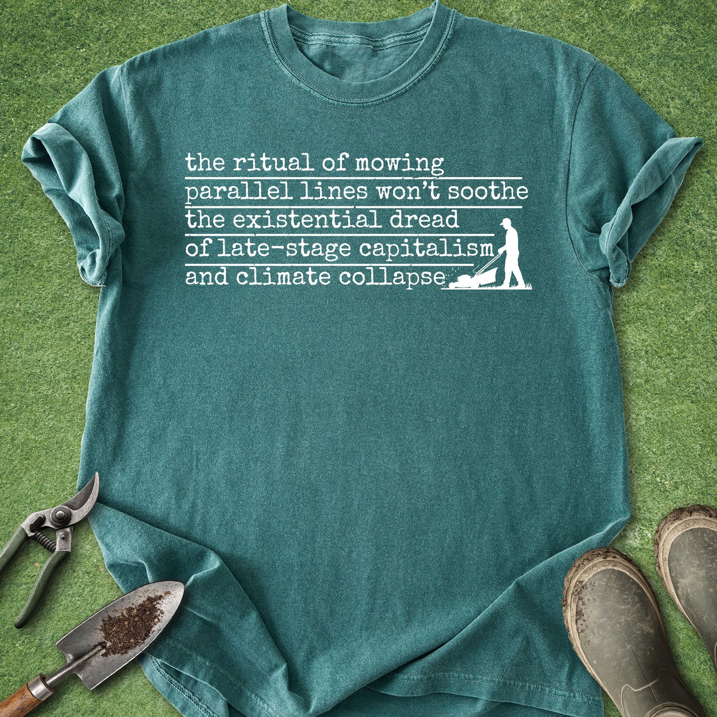 Teal t-shirt with printed text and graphic on a grass background