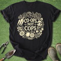 Black t-shirt with 'Co-ops Not Cops' design on a green background with gardening tools.