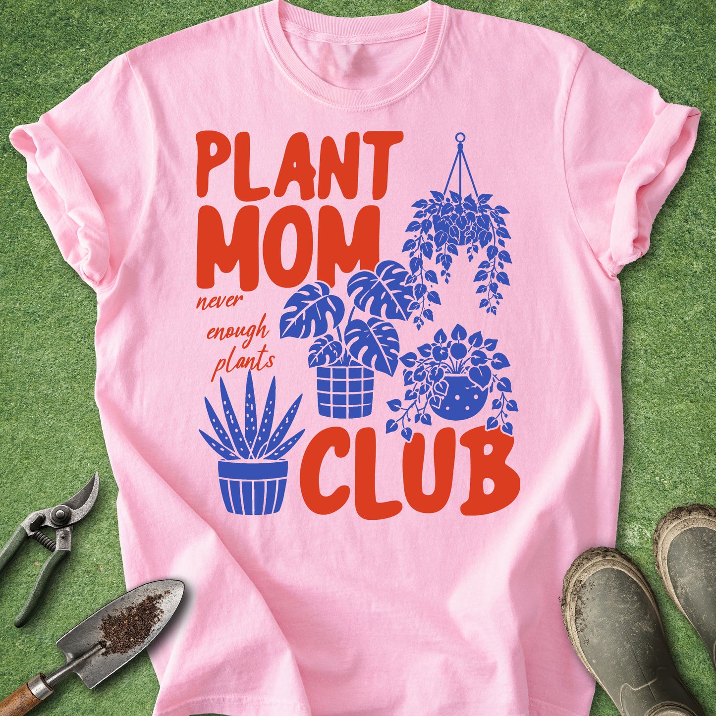 Pink t-shirt with 'Plant Mom Club' design on a green background with gardening tools.