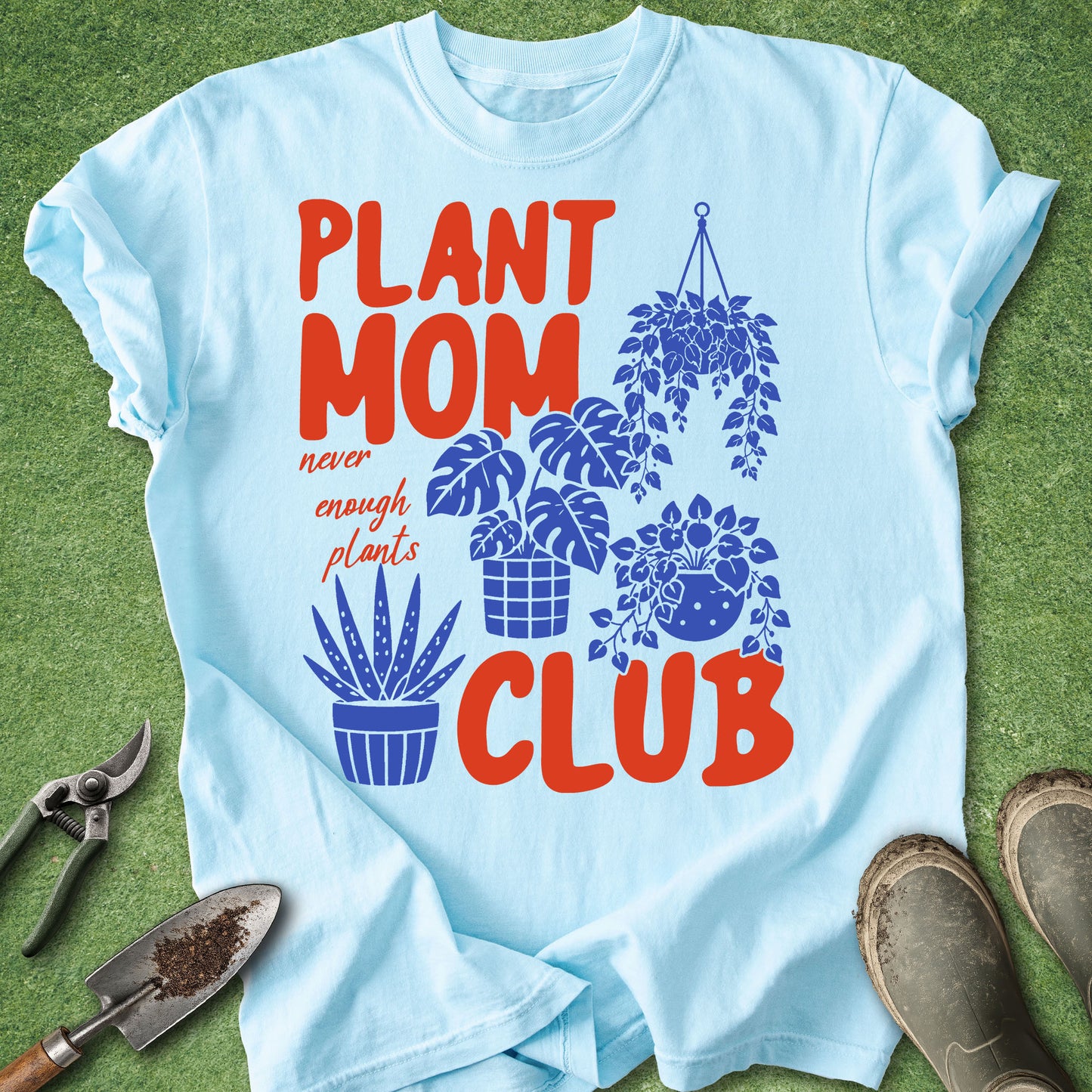 Light blue t-shirt with 'Plant Mom Club' design on a grass background