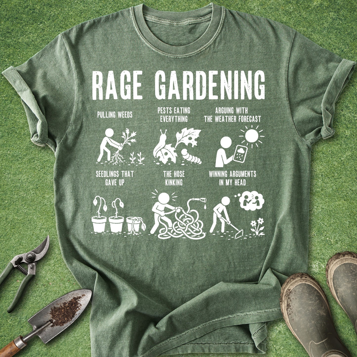 An olive green graphic t-shirt laid flat on a green grass-like surface, surrounded by gardening props including pruning shears, a trowel, and work boots. The shirt features a white 'RAGE GARDENING' slogan and six humorous gardening illustrations with text like 'PULLING WEEDS' and 'SEEDINGS THAT GAVE UP'.