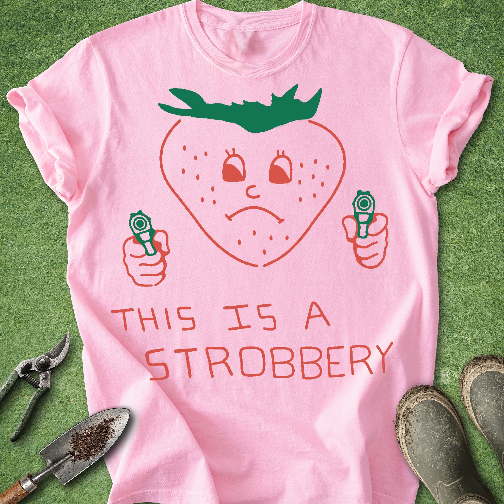 Pink t-shirt with a strawberry graphic and text on a green background