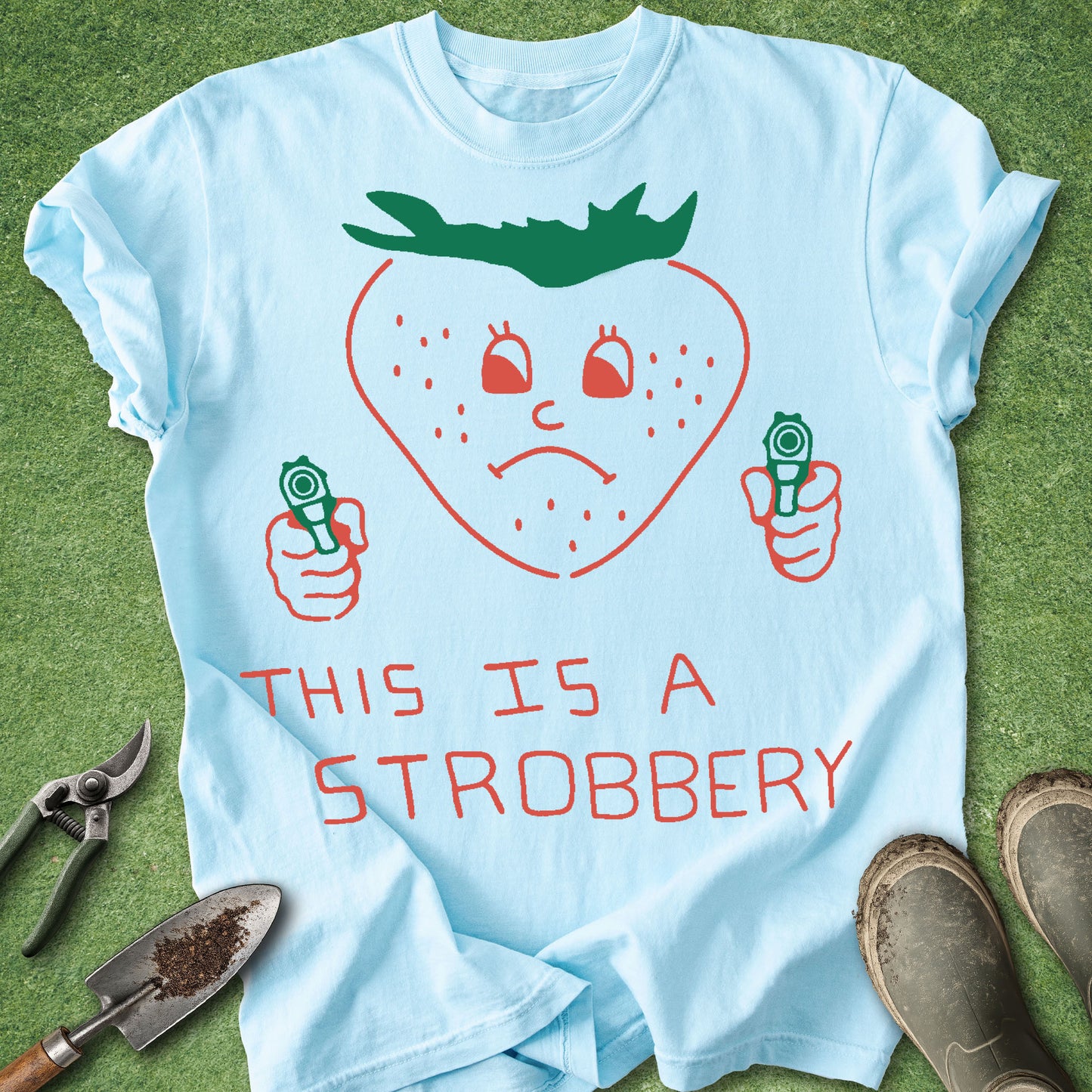 Light blue t-shirt with a strawberry graphic and text on a grass background
