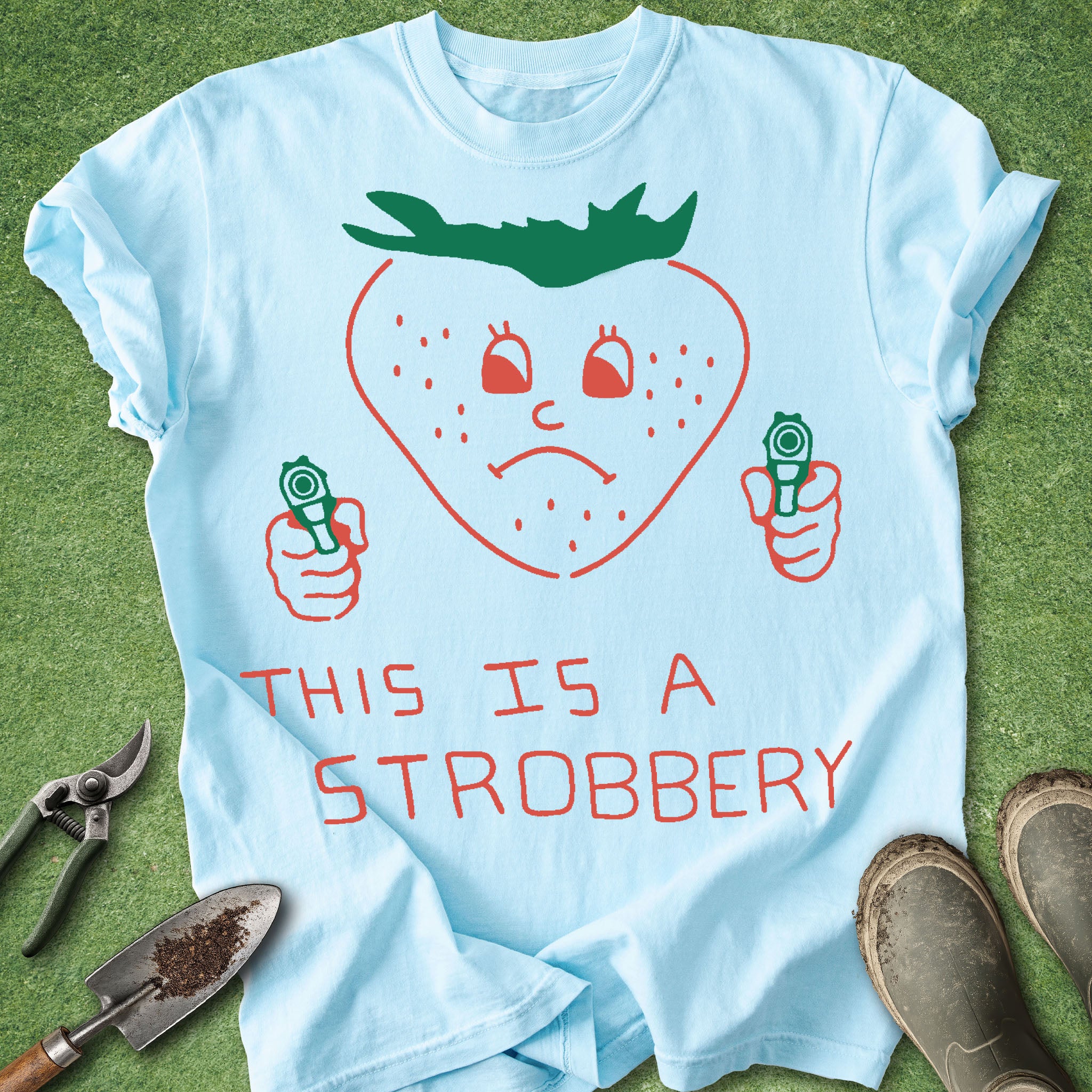 Light blue t-shirt with a strawberry graphic and text on a grass background