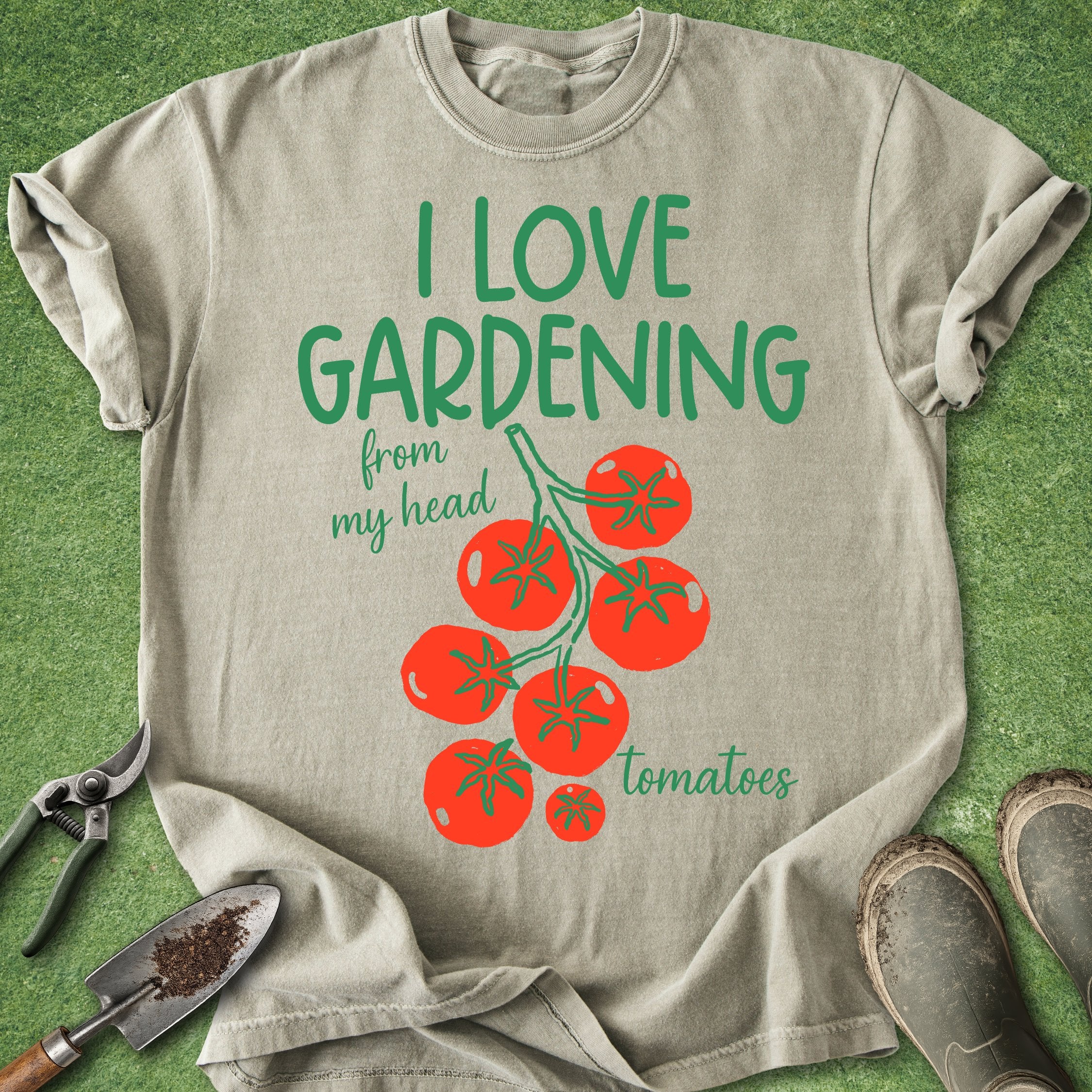 Beige t-shirt with 'I love gardening from my head tomatoes' text and tomato graphics on a grass background.