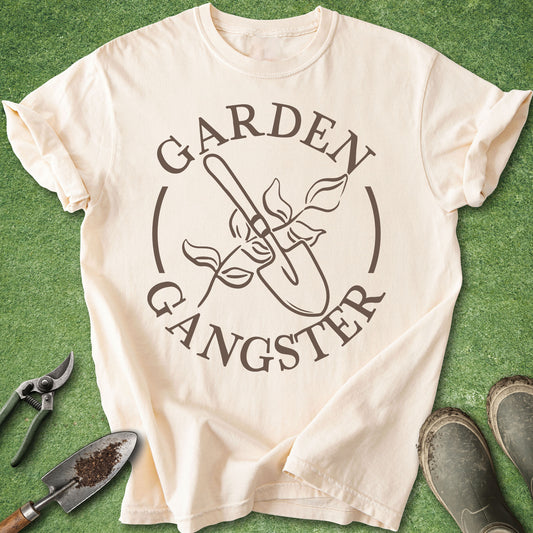 Funny gardening graphic t-shirt reading “Garden Gangster” with shovel and flower illustration on ivory shirt