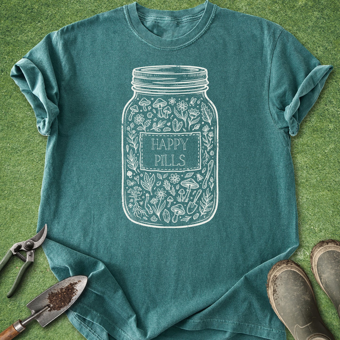 Teal t-shirt with 'Happy Pills' jar design on a grass background